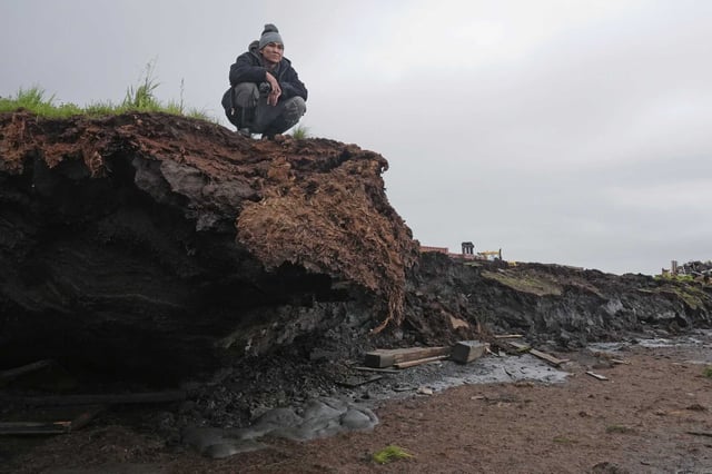 Charles Alexie stands along the coastal erosion that has eaten away at the riverbanks on Friday, Aug. 16, 2024, in Newtok, Alaska.