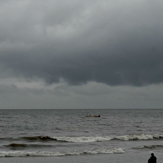 A boat sails on the horizon as dark clouds loom over the Arabian Sea near the Juhu Chowpatty beach in Mumbai on September 26, 2024. Storms and heavy rains have killed at least four people in India's financial capital Mumbai and the surrounding region, forcing schools to close and disrupting train services, officials and local reports said on September 26. (Photo by Indranil MUKHERJEE / AFP) (Photo by INDRANIL MUKHERJEE/AFP via Getty Images)