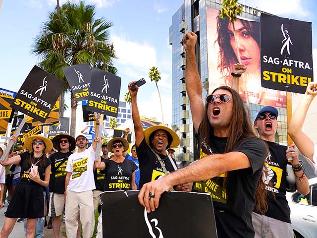 SAG-AFTRA member John Schmitt, second from right, and others carry signs on the picket line outside Netflix on Wednesday, Sept. 27, 2023, in Los Angeles. Hollywood's writers strike was declared over Tuesday night when board members from their union approved a contract agreement with studios, bringing the industry at least partly back from a historic halt in production. The actors strike continues in their bid to get better pay and working conditions. (AP Photo/Chris Pizzello)