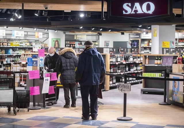The provincial Crown corporation in charge of liquor sales in Quebec is confirming that a computer error resulted in all its products being temporarily listed at 30 per cent off on its website. People wait to enter a SAQ outlet in Montreal, Tuesday, January 18, 2022. 