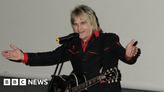 The Alarm singer Mike Peters on stage with a guitar around his neck