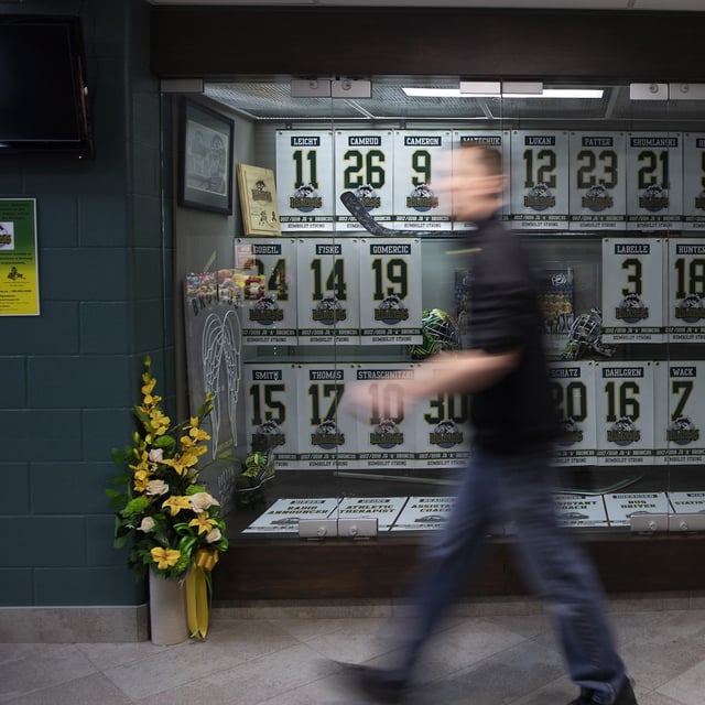 An attendee to the Humboldt Broncos Memorial service walks past a display at Elgar Petersen Arena in Humboldt , April, 6, 2019. THE CANADIAN PRESS/Kayle Neis