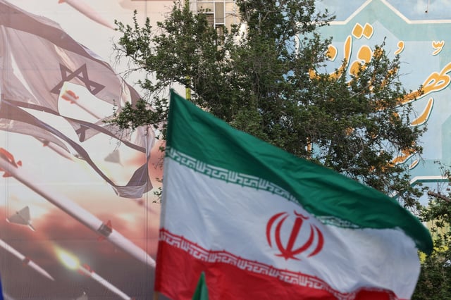 An anti-Israel billboard is seen next to the Iranian flag during a celebration following the IRGC attack on Israel, in Tehran, Iran, April 15, 2024. Majid Asgaripour/WANA (West Asia News Agency) via REUTERS/File Photo