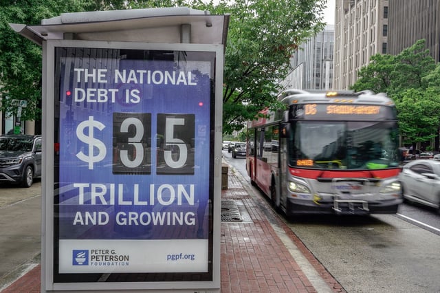 A Metrobus approaches a bus shelter at 18th and K St's NW where a poster and electronic billboard displays the current US national debt on August 8 in Washington, DC.