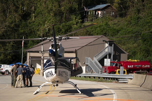 A helicopter pilot meets with people on the ground in the aftermath of Hurricane Helene on October 3, 2024, in Bat Cave, North Carolina.