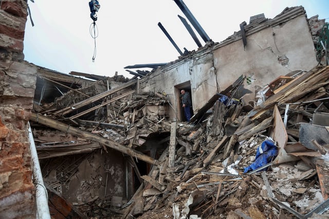 A local resident and a rescuer stand on debris of a building of local museum heavily damaged by a Russian missile strike, amid Russia's attack on Ukraine, in the town of Kupiansk, Kharkiv region, Ukraine April 25, 2023.  REUTERS/Viktoriia Yakymenko/File Photo