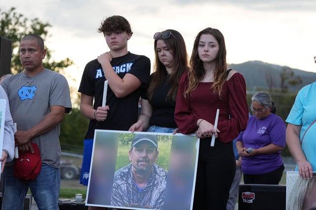 A photograph of Johnny Peterson is carried by his family during a candlelight vigil in Erwin, Tenn. Thursday, Oct. 3, 2024, for Helene flood victims.
