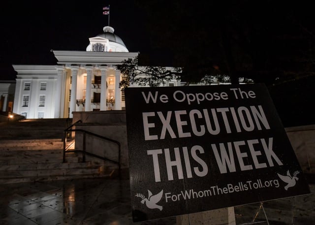 A sign stands in front of the Alabama State Capitol building as people watch a virtual vigil on Zoom from the capitol steps in Montgomery, Ala., on Thursday January 25, 2024 as they wait to hear news of the planned execution of Kenneth Eugene Smith.