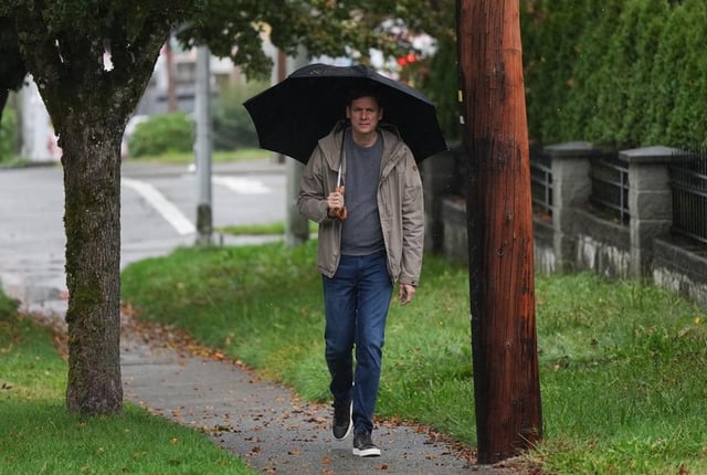 B.C. NDP Leader David Eby shields himself from the rain with an umbrella while walking from his bus to a house for a campaign stop in Surrey, B.C., on Monday, October 14, 2024. Voters along the south coast of British Columbia who have not cast their ballots yet will have to contend with heavy rain and high winds from an incoming atmospheric river weather system on election day. THE CANADIAN PRESS/Darryl Dyck
