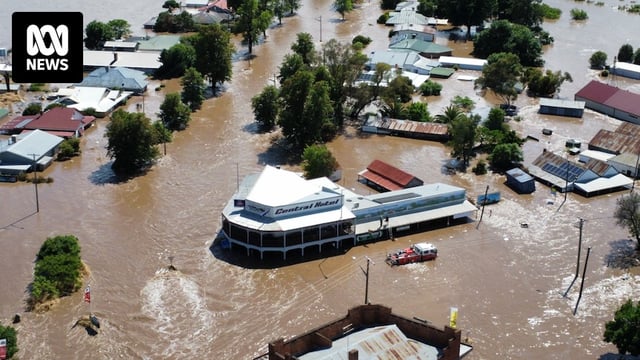 Aerial view of several homes and a large building under flood waters
