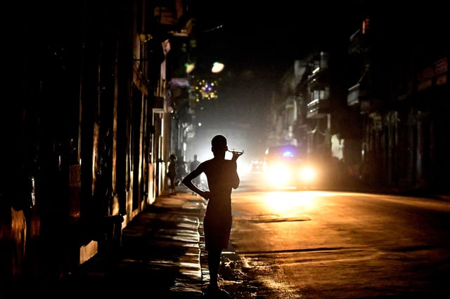 People stand in the street at night as Cuba is hit by an island-wide blackout, in Havana, Cuba, October 18, 2024. REUTERS/Norlys Perez