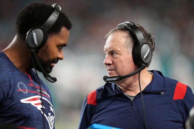 Head coach Bill Belichick of the New England Patriots and inside linebackers coach Jerod Mayo talk on the sidelines in the fourth quarter of the game against the Miami Dolphins at Hard Rock Stadium on January 09, 2022 in Miami Gardens, Florida.