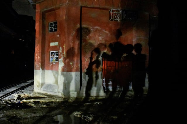 The shadows of people are cast on a wall through the lights of a passing car, as their street remains without electricity while Cuba is making progress restoring power to swaths of the Caribbean island nation, both in Havana and outlying provinces, after the entire national electrical grid crashed last Friday, in Havana, Cuba October 21, 2024. REUTERS/Norlys Perez/File Photo