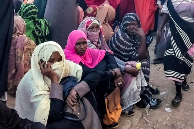 People from Khartoum and al-Jazira states, displaced by the war between Sudan's army and paramilitaries, wait to receive aid from a charity organisation in Gedaref, eastern Sudan, on December 30, 2023