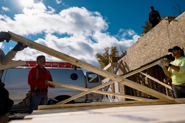 Workers inspect lumber outside a home under construction in New York State.