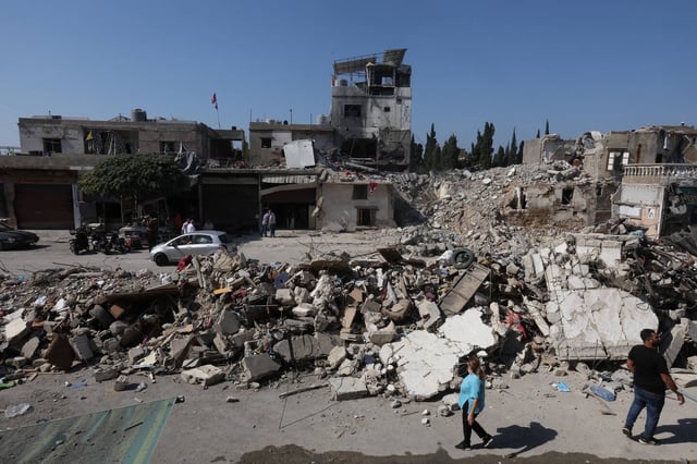 Des personnes marchent sur le site d'une frappe israélienne, au milieu des hostilités entre le Hezbollah et les forces israéliennes, à Sidon, au Liban, le 30 octobre 2024.