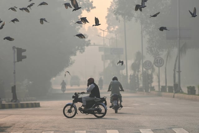 Commuters make their way amid smog in Lahore