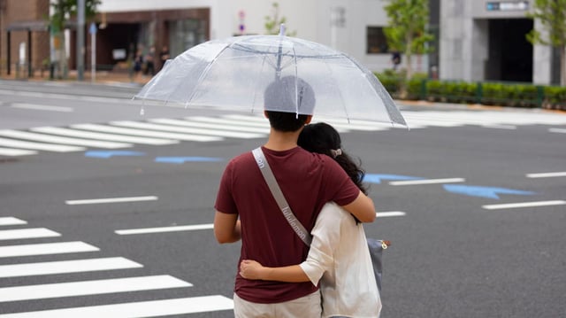 Ein junges Paar umarmt sich an einer Straße in Japan (Symbolbild).