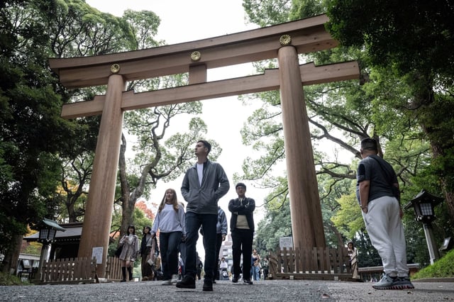 Tourists walk past a Torii gate at Meiji shrine in Tokyo on Nov. 14, 2024.