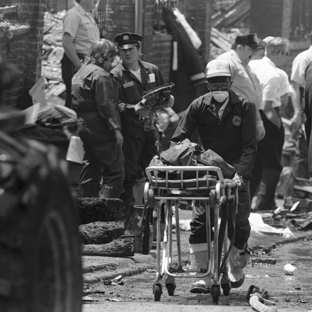 FILE - A worker transports the remains of a body found within the debris of the house of the radical group MOVE in West Philadelphia, May 15, 1985. (AP Photo/George Widman, File)