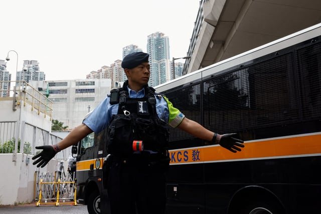 Un policier se tient en garde alors que le fourgon pénitentiaire transportant 45 activistes pro démocratie arrive au tribunal de West Kowloon, à Hong Kong, le 19 novembre 2024, pour entendre leur verdict.