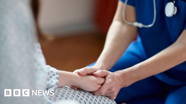 Cropped image of nurse in a blue uniform holding patient's hand - stock photo