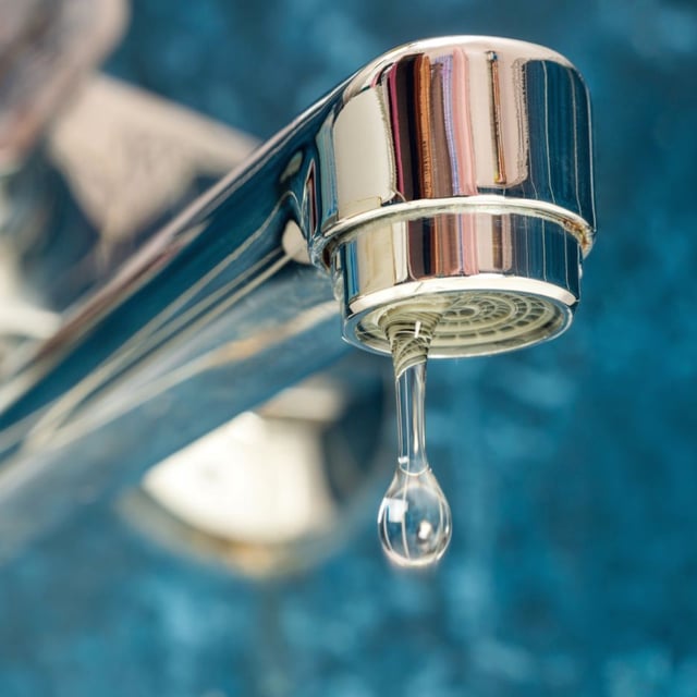 A drop of water drips from a leaky faucet. A newly characterized chloronitramide anion, likely present in the drinking water of over 100 million Americans, could pose a health risk, though more research is needed.