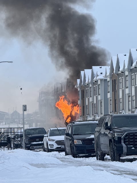 A photo provided to Global News shows fire and a plume of black smoke coming from a row of townhouses in the community of Mahogany in S.E. Calgary. 