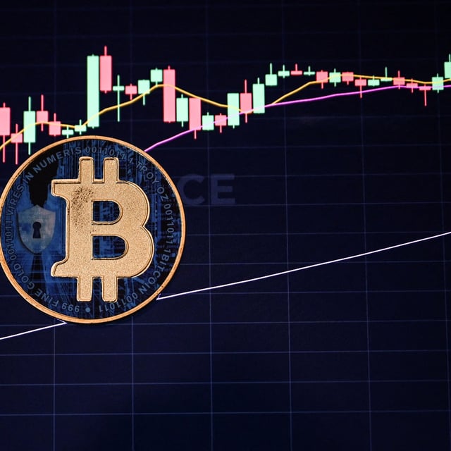 This illustration photograph taken on November 22, 2024 in Istanbul shows a coin imitation of the Bitcoin crypto currency arranged beside a screen displaying a trading chart. Most markets gained Friday after a bounce on Wall Street, while bitcoin continued its march higher to move within touching distance of the $100,000 mark.