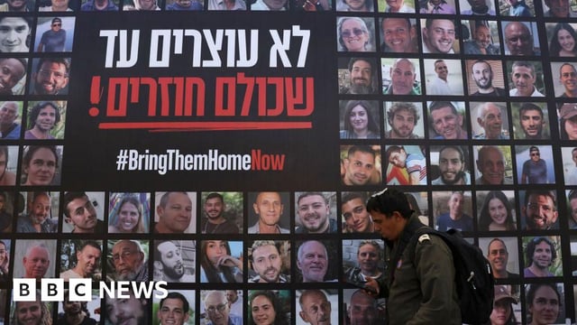A man walks past a poster displaying dozens of people taken hostage by Hamas into Gaza.