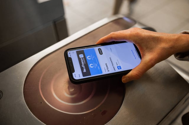 This photograph shows a person holding an iPhone equipped with a Paris Metro Navigo pass in a metro station in Paris, on May 24, 2024. Since May 21, 2024, tickets for the Paris transport system have been available on Apple's iPhone and Apple Watch, allowing for the first time the opportunity validate to travel on the network on apple devices. (Photo by Antonin UTZ / AFP)