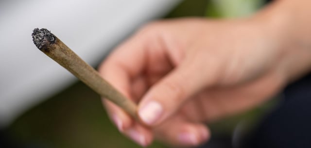 Eine Frau hält auf einer Hanfmesse einen Joint in der Hand (Archivfoto)