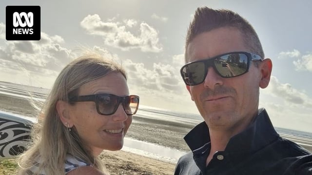 A man and woman taking a selfie on a beach.