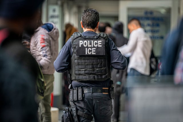 An ICE agent monitors hundreds of asylum seekers being processed on June 6, 2023, in New York City.