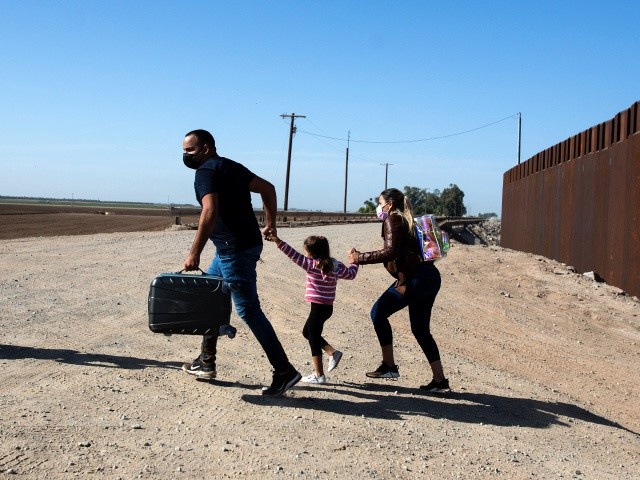 A family of migrants from Cuba runs across the border by the wall separating the United States and Mexico to turn themselves over to authorities on May 13, 2021 in Yuma, Arizona. - Apprehensions of undocumented immigrants at the US border with Mexico rose to a fresh 15-year high in April as the Biden administration failed to deter migrants, official data showed on May 11, 2021.US Customs and Border Protection reported it had interdicted 178,622 people trying to enter the United States without official immigration papers last month, up more than 5,000 from March's high numbers. (Photo by RINGO CHIU / AFP) (Photo by RINGO CHIU/AFP via Getty Images)