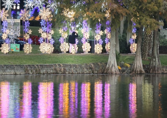 Strollers enjoy the festive holiday lights at Lake Eola Park on Tuesday, Dec. 3, 2024. On Saturday thousands lined up to see the annual holiday drone show but it ended abruptly after drones collided and fell from the sky into the crowd. One drone struck a little boy and left him hospitalized.  (Stephen M. Dowell/Orlando Sentinel)