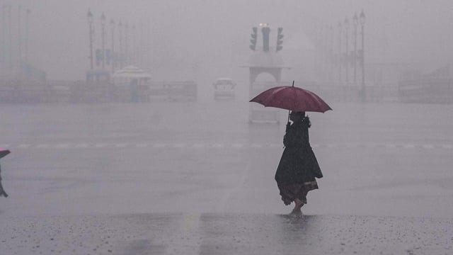 People move amid rain at Vijay Chowk, in New Delhi on Friday,