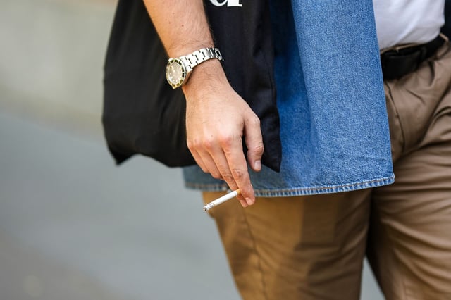 An attendee at a show holds a cigarette during Milan Fashion Week in 2022.