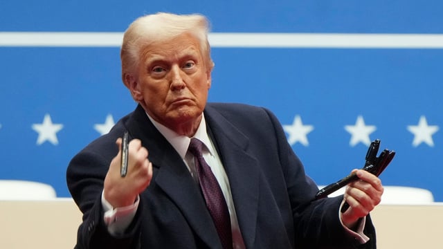 President Donald Trump throws pens used to sign executive orders to the crowd during an indoor Presidential Inauguration parade event in Washington, Monday, Jan. 20, 2025. (AP Photo/Matt Rourke)