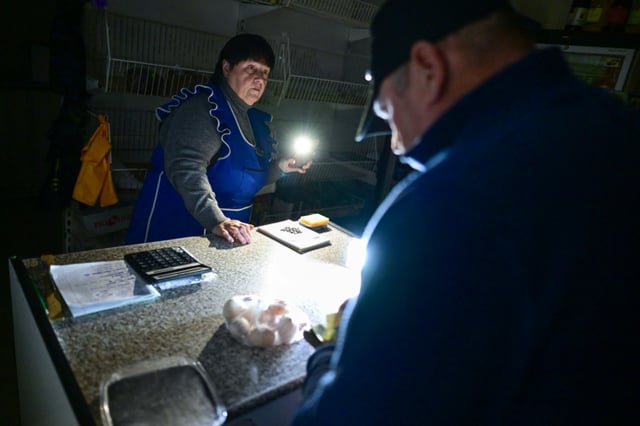 Valentina Gora sells eggs and bread to customers using the flashlight from her phone