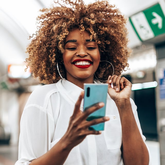 In this stock photo, a woman is pictured is pictured using her smartphone.