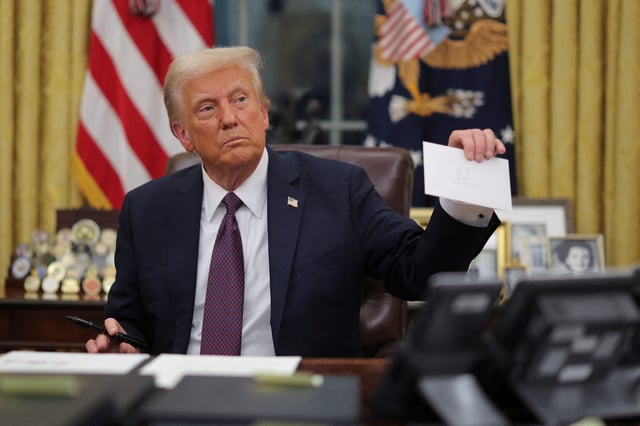 President Donald Trump, amid signing executive orders and pardons, holds a letter to him from former President Joe Biden on Jan. 20, 2025, his first day back in the Oval Office.