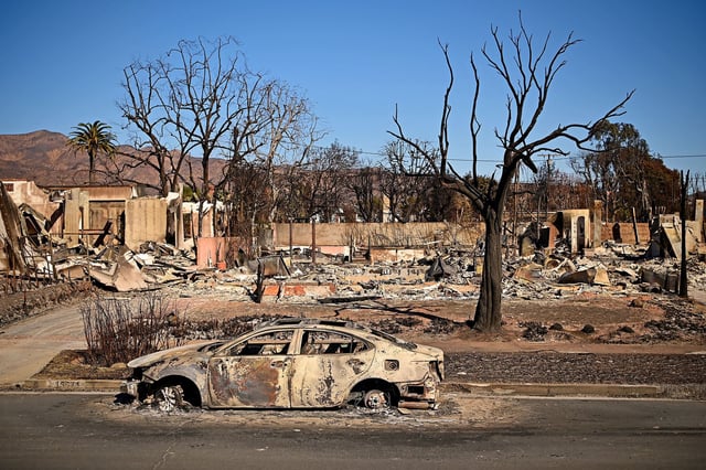 A burnt car sits outside a destroyed home amid the rubble of the fire-ravaged Pacific Palisades Bowl Mobile Estates in Los Angeles, California, on January 13, 2025. Firefighters were battling massive wildfires on January 13 that have ravaged Los Angeles and killed at least 24 people, with officials warning of incoming dangerous winds that could whip up the blazes further. (Photo by AGUSTIN PAULLIER / AFP) (Photo by AGUSTIN PAULLIER/AFP via Getty Images)
