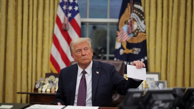 FILE PHOTO: U.S. President Donald Trump holds former United States President Joe Biden's letter on the day he signs documents as he issues executive orders and pardons for January 6 defendants in the Oval Office at the White House on Inauguration Day in Washington, U.S., January 20, 2025. REUTERS/Carlos Barria/File Photo