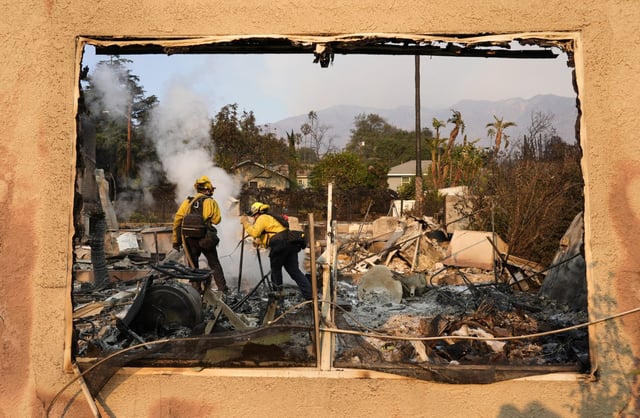 Firefighters extinguish burning embers at a house in Altadena, Calif., on Jan. 9. 