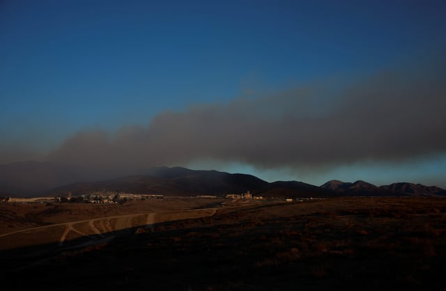 Smoke rises as firefighters battle the Border 2 fire next to the Mexican border, in the hills east of the Otay Mesa neighborhood of San Diego, California on January 23, 2025.