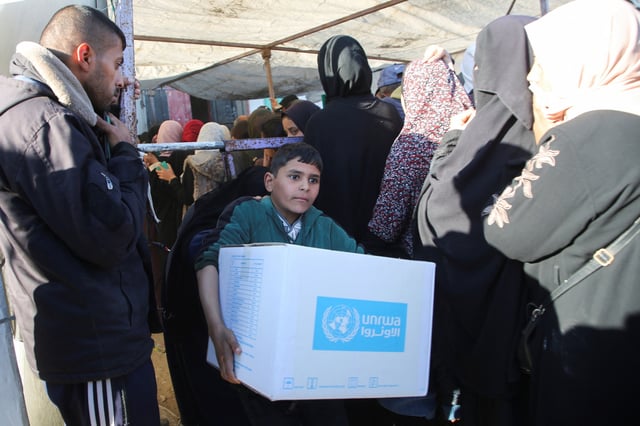 Un garçon palestinien porte une boîte d’aide fournie par l’Unrwa, suite à un cessez-le-feu entre Israël et le Hamas, à Khan Younis dans le sud de la bande de Gaza, le 21 janvier 2025.