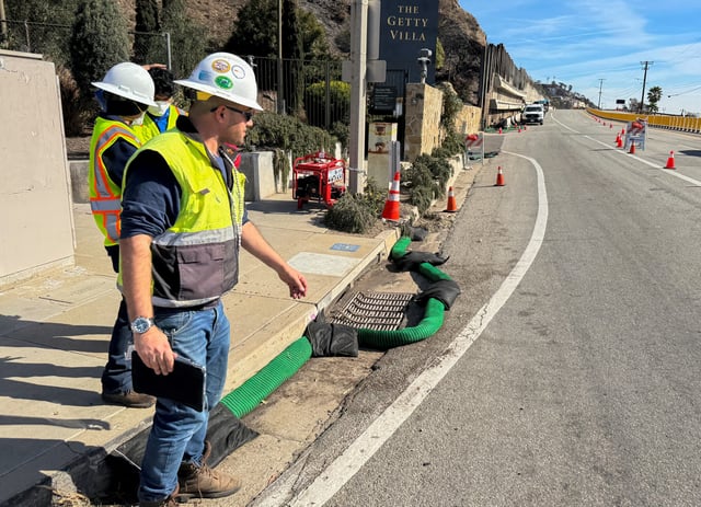 Workers place a silt sock to keep contaminants from entering storm sewers following the Palisades Fire in Los Angeles on Jan. 24, 2025.