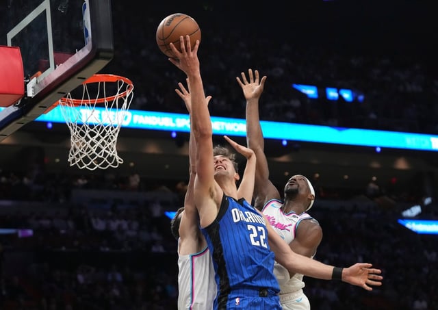 Magic forward Franz Wagner (22) goes to the basket as Heat center Bam Adebayo, right, defends during the first half on Monday night in Miami.  (AP Photo/Lynne Sladky)
