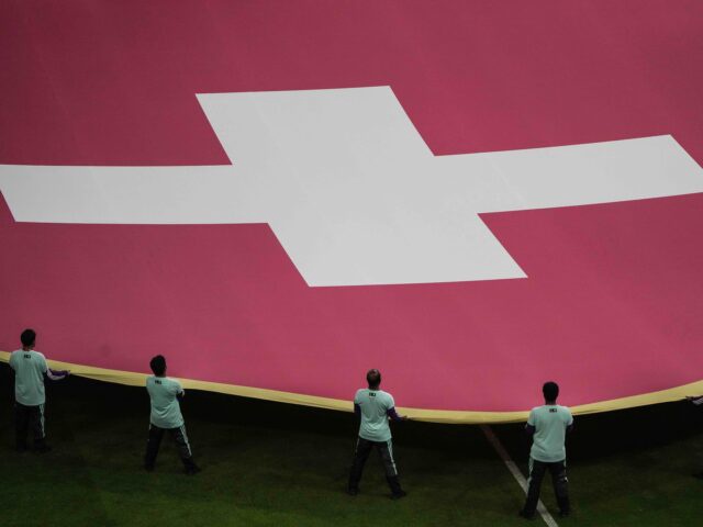 Volunteers hold a giant flag of Switzerland prior the start of the World Cup round of 16 soccer match between Portugal and Switzerland, at the Lusail Stadium in Lusail, Qatar, on Tuesday, Dec. 6, 2022. (AP Photo/Ariel Schalit)